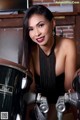 A woman in a black dress sitting next to a drum set.