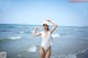 A woman in a white bathing suit standing in the ocean.