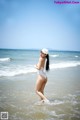 A woman in a white bathing suit standing in the ocean.