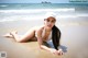 A woman in a white bikini laying on the beach.