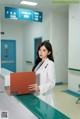 A woman in a white lab coat holding a red folder.