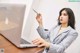 A woman sitting at a desk with a laptop and a pen.