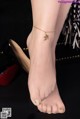 a woman wearing a gold ankle bracelet with a bird on it