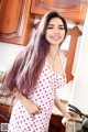 A woman in a pink polka dot dress standing in a kitchen.