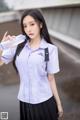 A woman in a school uniform holding a water bottle.