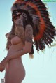 A naked woman wearing an orange and black headdress.