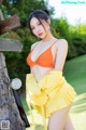 A woman in an orange bikini top and yellow skirt posing for a picture.