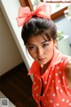 A woman in a red polka dot dress with a large bow in her hair.