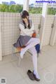 A woman in a school uniform sitting on a chair.