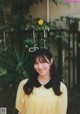 A woman in a yellow dress standing in front of a fence.