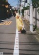 A woman in a yellow dress is walking down the street.