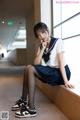 A woman in a school uniform sitting on a ledge.