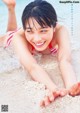 A woman in a red and white bikini laying on the beach.