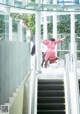 A woman in a pink dress is jumping on an escalator.