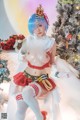 A woman in a red and white outfit sitting in front of a Christmas tree.