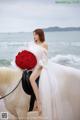 A woman in a white dress sitting on a white horse.