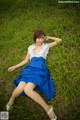 A woman in a blue skirt is laying in the grass.