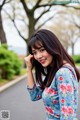 A woman in a blue floral dress posing for a picture.