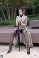 A woman sitting on a bench holding an umbrella.