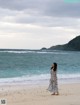 A woman standing on a beach next to the ocean.