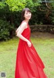 A woman in a red dress standing in the grass.