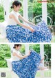 A woman sitting on a white chair wearing a blue and white floral skirt.