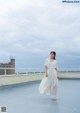 A woman in a white dress standing on a roof.