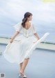 A woman in a white dress is standing on a roof.