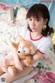 A woman sitting on a bed holding a teddy bear.