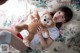 A woman laying on a bed holding a teddy bear.