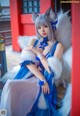 A woman in a blue and white dress sitting on a bench.