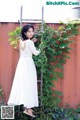 A woman in a white dress standing next to a ladder.