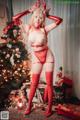 A woman in a red lingerie posing in front of a Christmas tree.