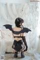 A woman in a black lingerie with a bat on her back.