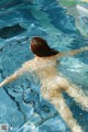 A naked woman in a swimming pool with her arms outstretched.