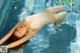 A woman in a white bodysuit floating in a pool.