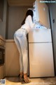 A woman standing in front of a refrigerator in a kitchen.