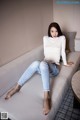 A woman sitting on a white couch with her legs crossed.