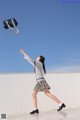 A woman in a school uniform throwing a bag in the air.