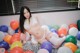 A woman in a white lingerie sitting on a bed of balloons.