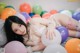 A woman laying on top of a bed of balloons.