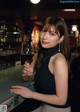 A woman holding a glass of wine at a bar.