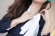 A woman in a business suit adjusting her tie.