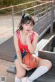 A woman sitting on a bench holding a basketball.