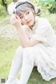 A woman in a white dress sitting on the grass.